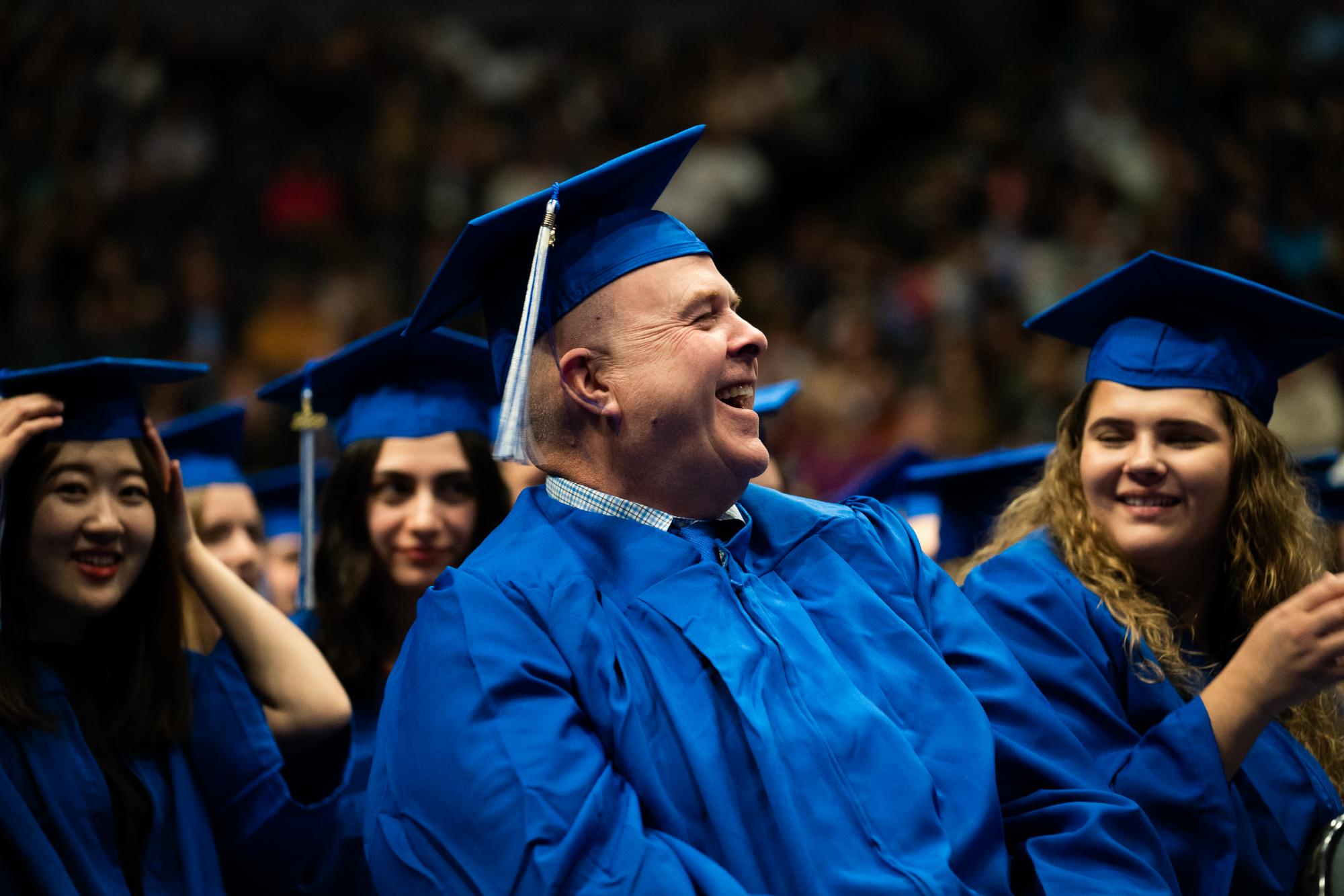 adult learner in blue graduation cap smiling